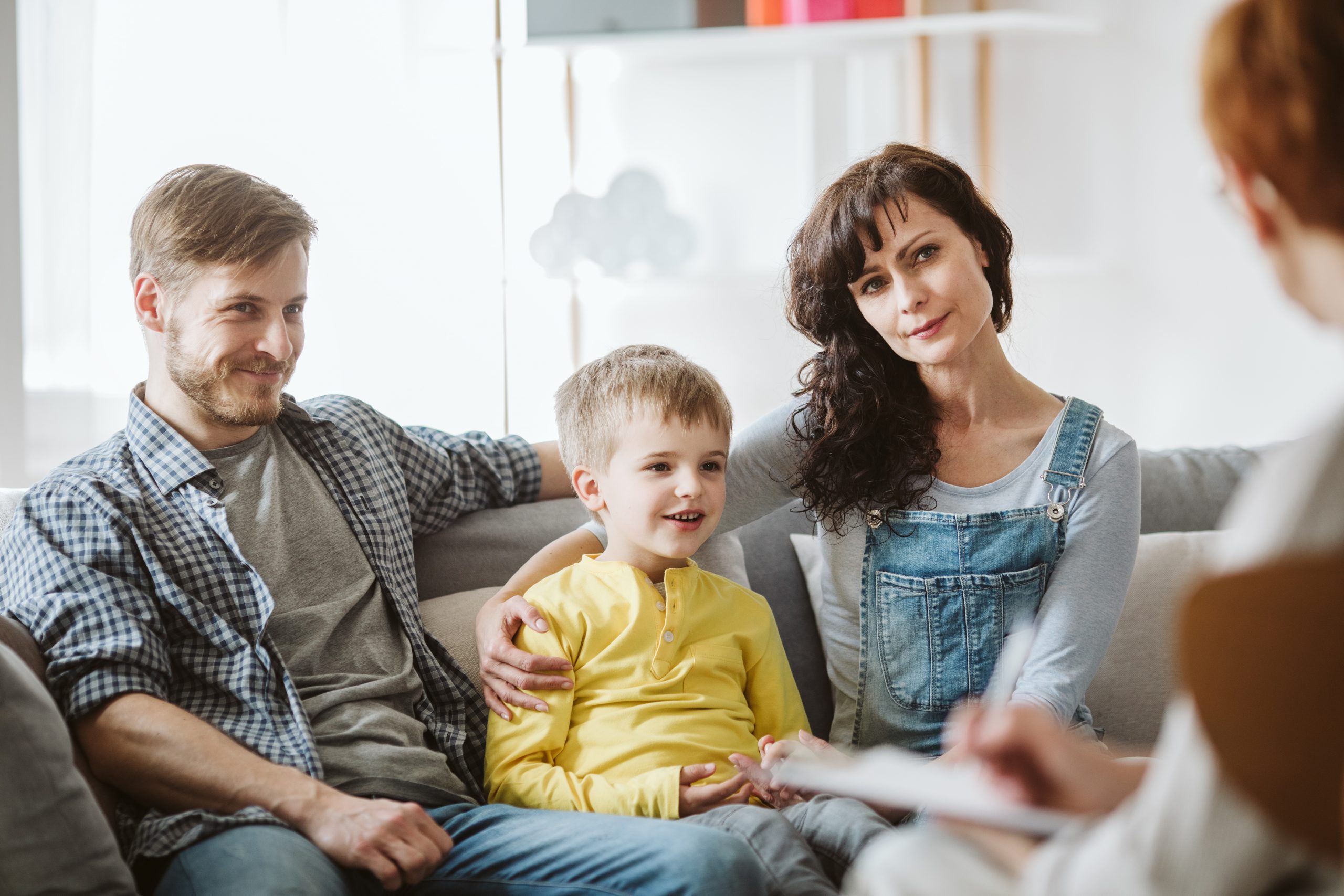 Caring parents and misbehaving boy during therapy session with counselor