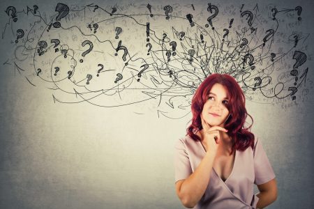 Young redhead pensive woman having questions holding hand under chin thoughtful looking at arrows and mess going out of head.